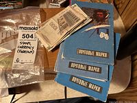 Three blue books labeled in Russian with a pipe-smoking man, feather, and theatrical masks, showing the collection of stamps and foreign currency notes on top.