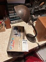 Vintage metal desk lamp on workbench alongside original boxed horn, labeled MaxSold 417.