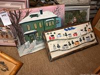 Full view of four wall art pieces including two paintings and two village scene wooden panels