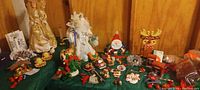 Wide image showing entire lot with angel tree toppers, assorted ornaments, Santa figure, and nativity pieces on wood-paneled shelves