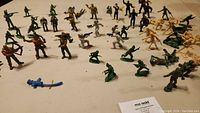 Wide view of mixed army men in green, tan, and black posing with weapons and in action stances
