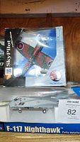 Photo showing boxed Sky Pilot Collection Spitfire plane with camouflage paint and RAF roundels and boxed Air Command F-117 Nighthawk model plane below it.