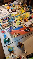Full view of assorted toys and novelty items including figurines, silly straws, paint transfer book, and more