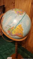 Photo showing globe from the southern hemisphere side, including Australia and Antarctica, mounted on wooden and metal stand.
