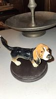 Glossy Beagle dog figurine mounted on dark wood stand from side angle showing detailing in coat and expression.