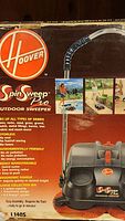 Full view of the Hoover Spin Sweep Pro outdoor sweeper on packaging showing product features and images of use.