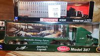 Photo of the two die-cast truck models in their original packaging showing brand, series and scale.