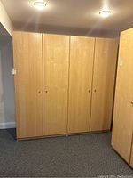 Front view of two adjacent light maple laminate wardrobe cabinets with four doors
