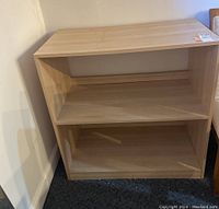 Front and side view of light wood bookcase with two shelves, showing condition and structure