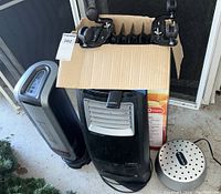 Photo showing three heating and drying devices: Lasko ceramic heater, Lasko radiator heater, and West Marine air dryer.