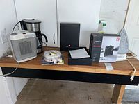 Full lot on wooden table showing space heater, coffee maker, iron, sharpener, wine opener, and fire alarm