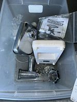 Overview of the Mega Force 3000 Series meat grinder parts including metal housing, white plastic mechanism, metal grinder plates, and manual in plastic bag