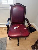 Front view of the vintage office chair showing red leather upholstery with wear and brass nailhead trim.