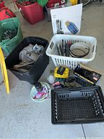 Photo showing backpacks, plastic bins, baskets holding camping and emergency items, tools, and small accessories on garage floor.
