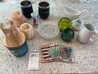 Wide shot showing the entire assortment of salt block candle holders, insulated cups, dessert plate, ceramic pitchers, glass votives, coasters, and small candle jar set on countertop.