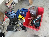 Overview of lot showing a red plastic bin with various hand tools including hammers and cordless drill, black toolboxes, power cords, and a small pump.