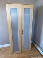 Front view of wardrobe cabinet showing two frosted glass panel doors with wooden handles
