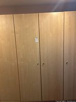 Front closed view of the wardrobe cabinet with four doors in a light wood finish.