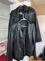 Two black leather women's jackets hanging on hangers. One Maxima long coat size XS, one shorter Colebrook & Co. jacket size M.