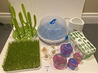 Overview of all baby feeding items including the Boon Grass and Sprig drying racks, Munchkin sterilizer, Tommee Tippee bottle warmer, dishwasher organizer, formula containers and disposable nipples