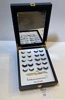 Open Lash Vanity Storage Case showing mirror with lights and 10 pairs of lashes, lash applicator, and lash glue inside.