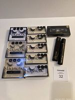 All 6 pairs of Velour magnetic eyelashes arranged in two columns and three rows, beside 3 magnetic lash kits and two tubes of adhesive liners.