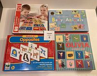 Top view of 4 toddler matching games - Converse Matching Game, Baby Animals puzzle pairs, Match It! Opposites, and Olivia Matching Game on flat surface.