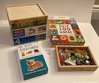 Photo showing all items in lot: three boxed sets of Melissa & Doug wooden puzzles, My First Animals picture cards, First 100 Words game box, and tray with wooden animal magnets.