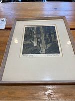 Full frontal view of framed etching with white mat under light wood frame