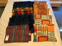 Complete lot of wool blankets and decorative pillows arranged on bed.