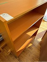 Front and side view of wooden bookcase showing shelving and surface condition under natural lighting.