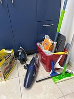 Overview of cleaning tools on floor including Shark handheld vacuum, bucket with mop and squeegees, and packing box.