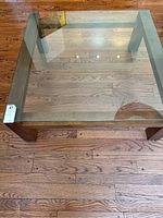 Full top-down view of square coffee table with glass top and wooden frame
