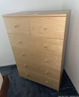 Front view of the light wood MDF dresser showing five drawers with wooden knobs.