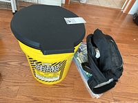 Photo of the second yellow plastic bucket with black lid and label showing content types and customer information box.