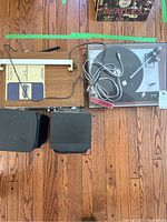 Overview of the Thorens turntable on wooden floor with dust cover and two speakers