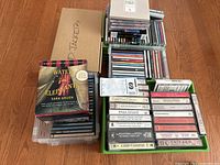 Stack of assorted music CDs including boxed sets and individual albums in plastic cases, with visible titles such as Water for Elephants audiobook nearby.