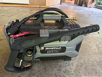 Side view of main pressure washer unit with attached spray gun and hose