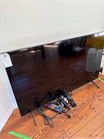 Samsung 44 inch TV with remote control and power bar on wooden floor.