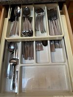 View of metal spoons, forks, and knives organized in a plastic drawer cutlery tray