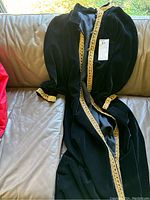 Full view of black velvet robe laid out on a couch showing gold lace trim on front and cuffs.