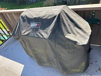 Weber grill covered with branded protective cover