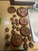 Overview of 20 copper molds including large round animal and figure designs, and smaller shaped molds.