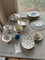 Photo of entire set on marble surface showing various plates, bowls, cup and saucer, covered dish, floral vase, and hexagonal pedestal bowl.