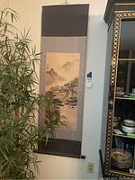 Full view of the hanging scroll art showing the entire landscape scene bordered by patterned fabric.