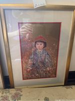 Full view of framed art depicting a child in traditional clothing with a gold frame and glass cover.