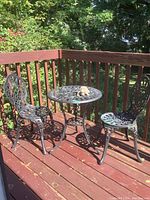 Wide view of the outdoor metal bistro set on wooden deck with table, two chairs and turtle decor
