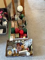Photo showing assorted candles, including red and green pillar candles, tealights, wax melts, reed diffuser sticks, and various holders in boxes.