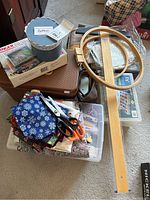 Overview photo showing plastic sewing basket filled with clear containers holding fabric, thread, scissors, embroidery hoops, and a wooden T-square