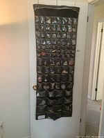Full view of door hanging organizer filled with brooches and pins in each clear pocket.